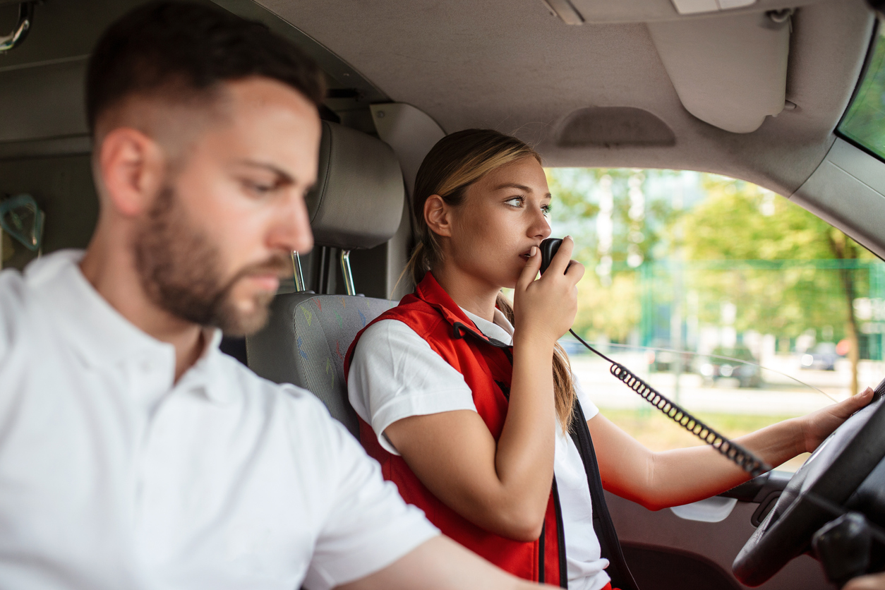 Paramedic answers an emergency call from an ambulance. Young woman answering a call in an ambulance. She's with her colleague.